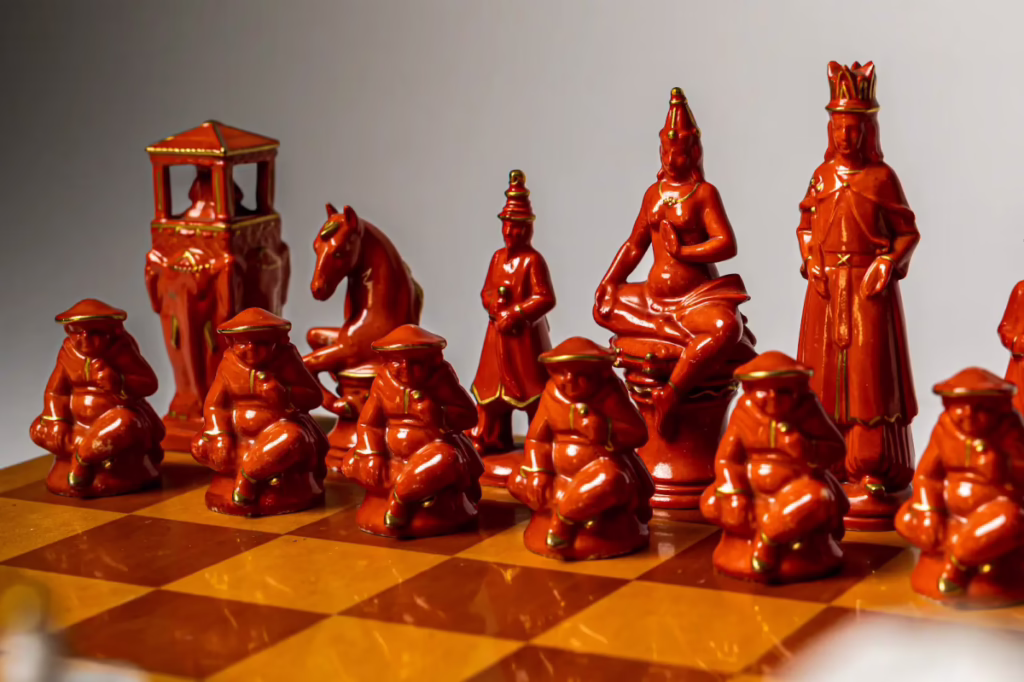 Close-up of the orange side of the Volkstedt set displaying queens in lotus position and pawns wearing conical hats.