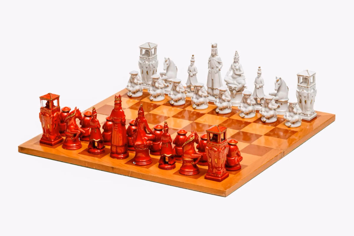 Full 1930s Volkstedt porcelain chess set featuring white and orange pieces detailed with gold accents and Asian-inspired figures.