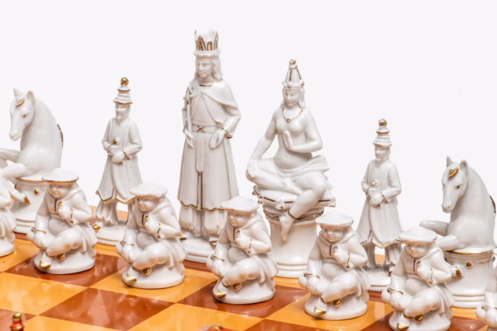 Close-up of the white side of the Volkstedt porcelain chess set, showing intricate royal figures and gold accents.